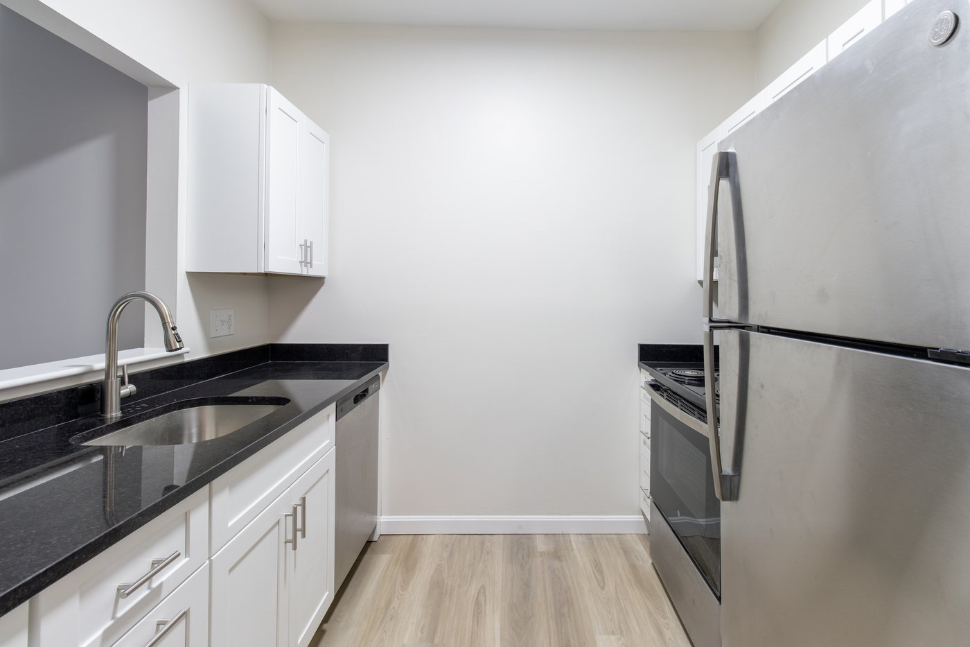 Renovated kitchen with white cabinets, granite counters and stainless appliances